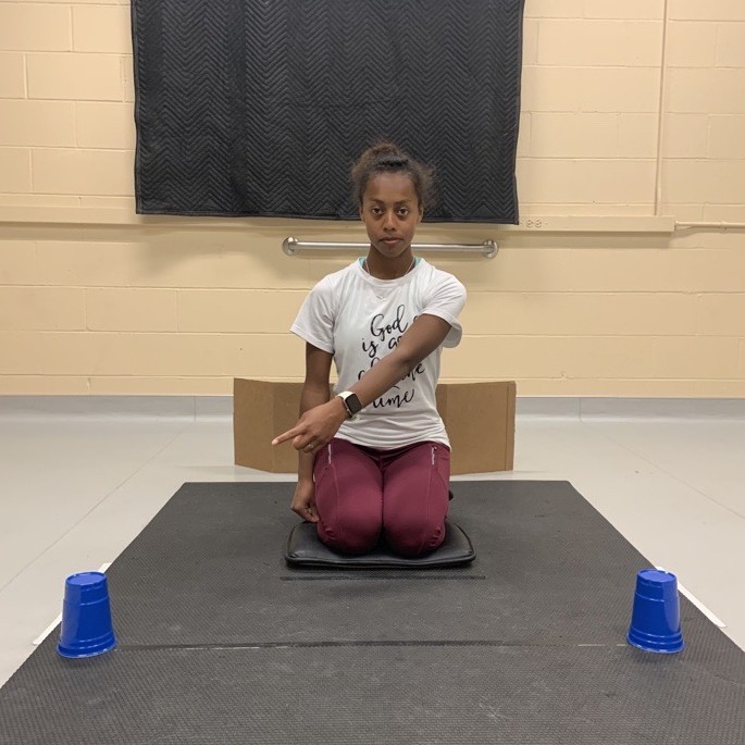 Image of person pointing to one of two blue cups.